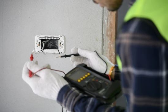Électricien de construction de maison utilisant voltmètre vérifier fil électrique qui a été préparé et installer avant d'assembler interrupteur de lumière pour la procédure de travail de sécurité